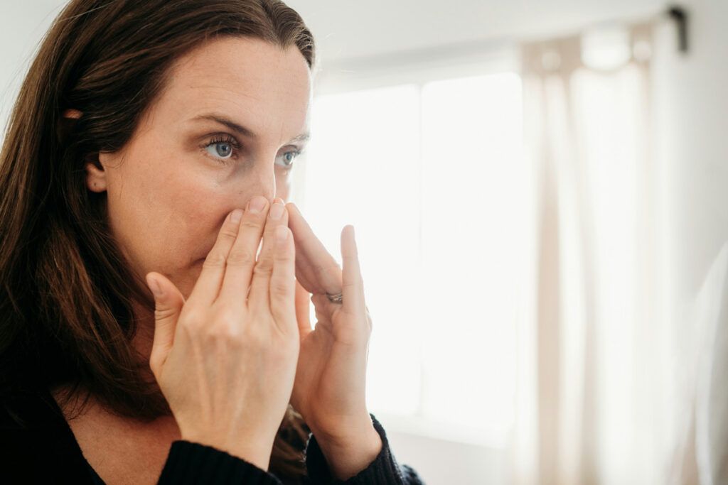 Person pressing their nose with both hands