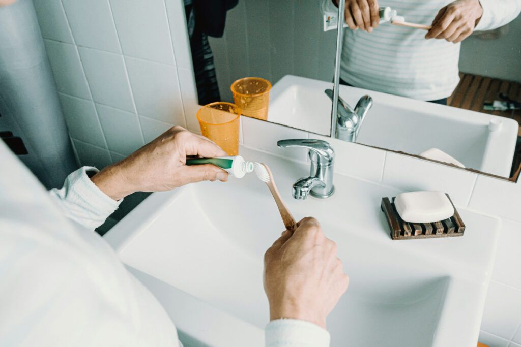 Person applying toothpaste to toothbrush