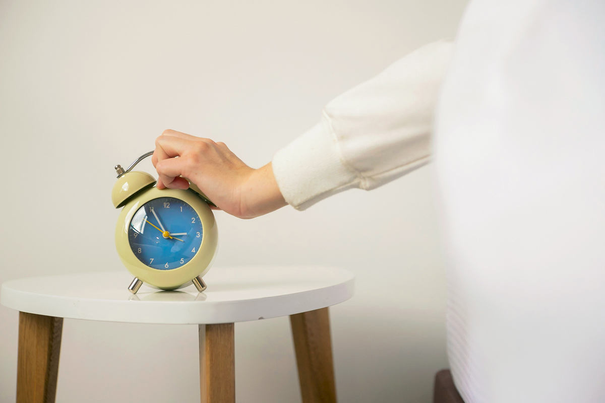 Person pressing an alarm clock