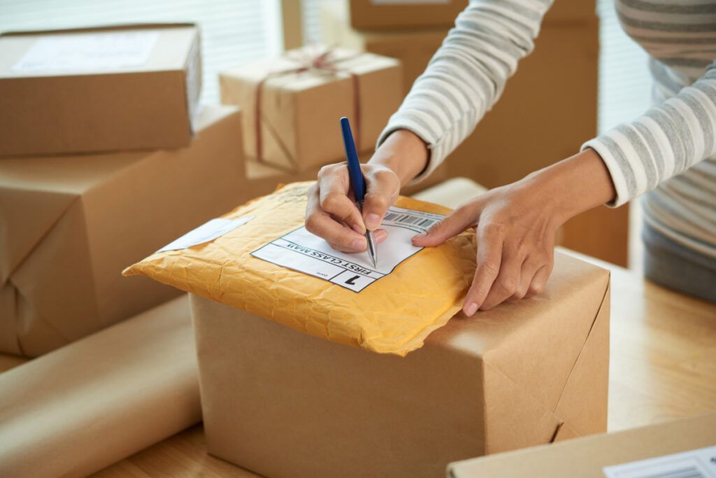 Person writing on package mailing label