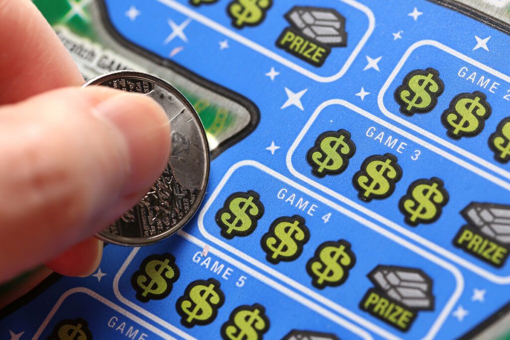 Person scratching a lotto scratcher with a coin