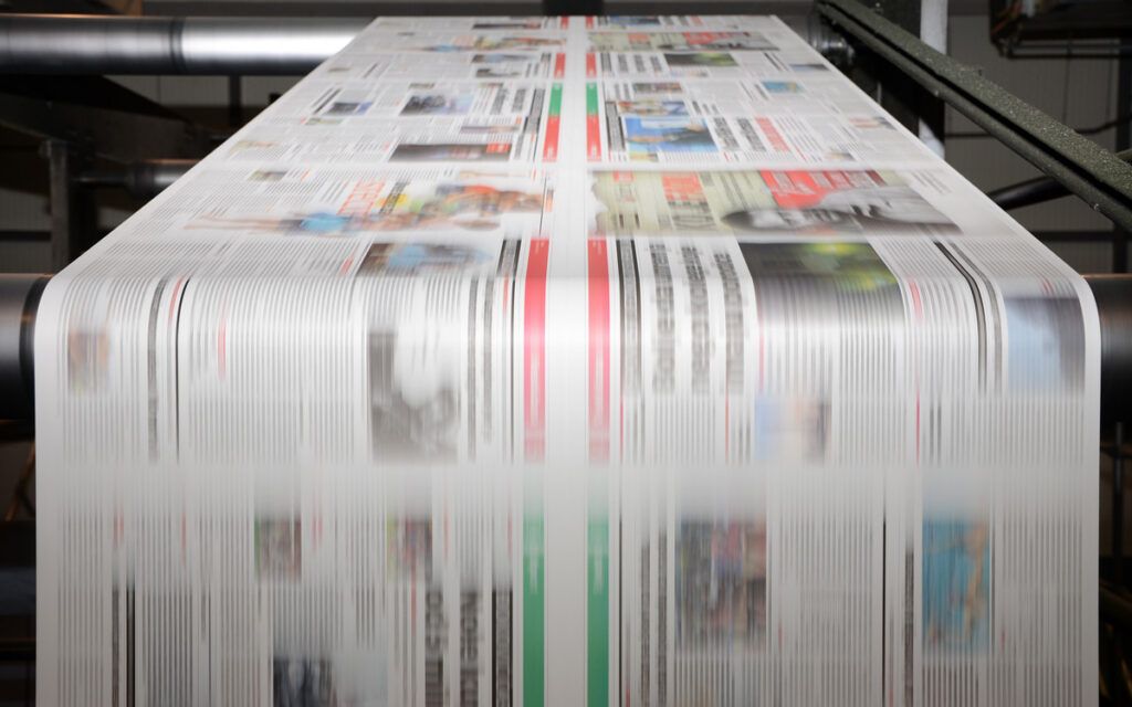 Newspapers being rolled through a machine