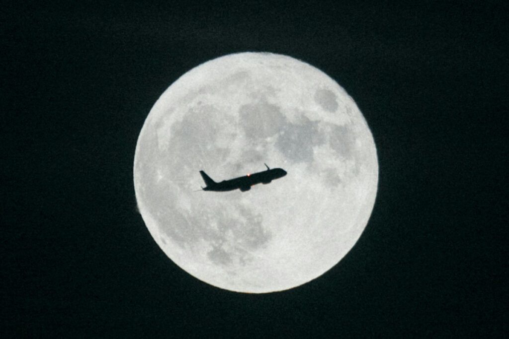 Silhouette of an airplane in front of the moon