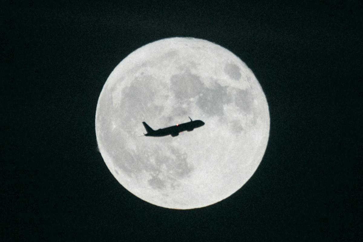 Silhouette of an airplane in front of the moon